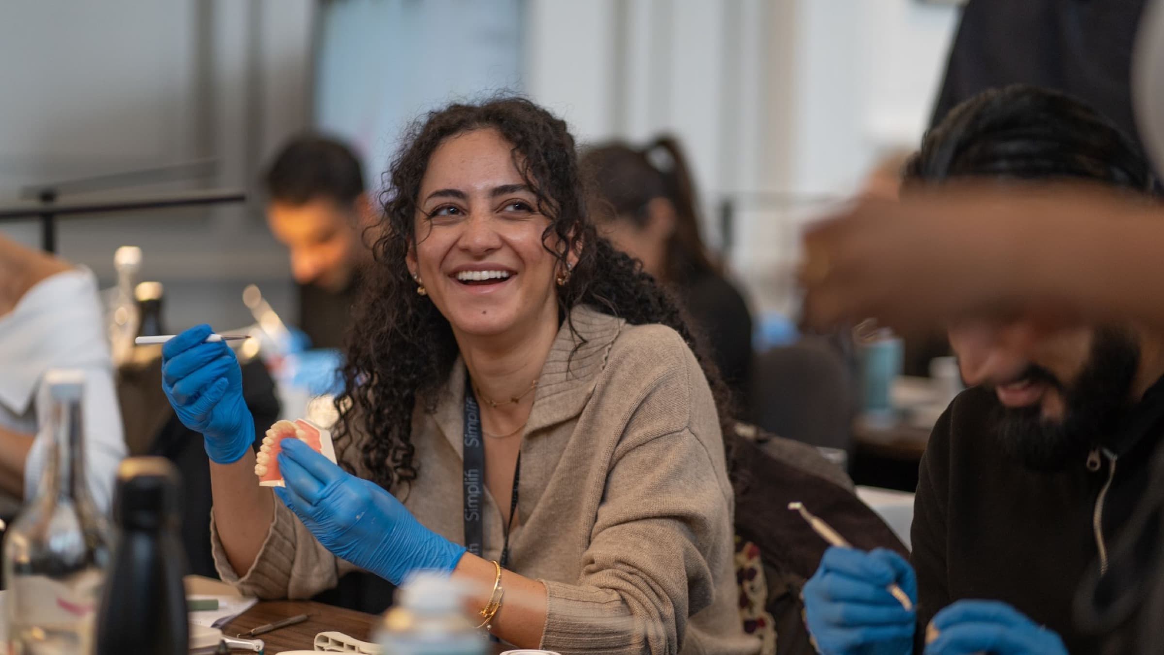A delegate laughing as she works on a typodont at a Simplifi Composite course