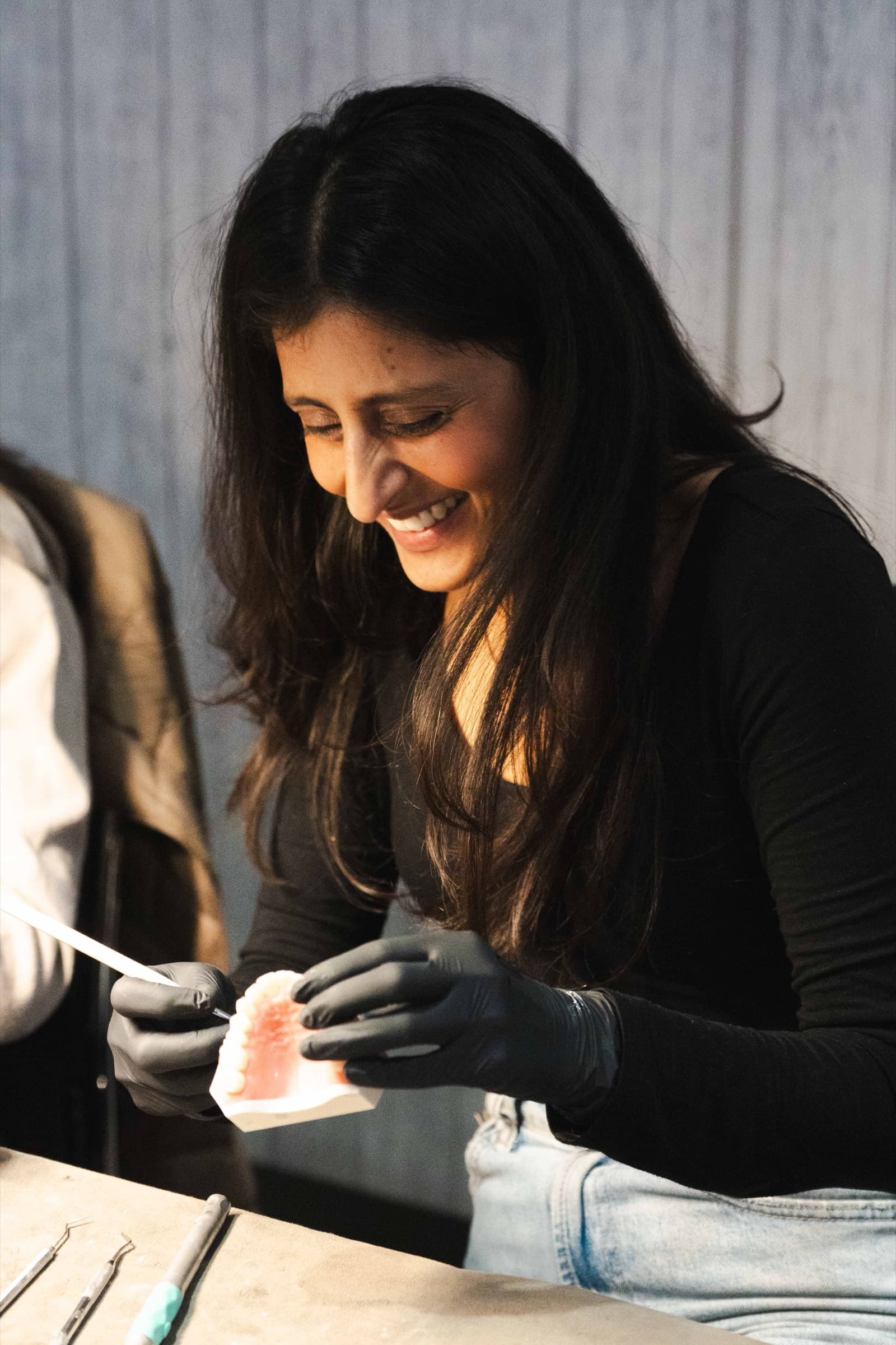 A delegate smiling while polishing a composite veneer on a typodont